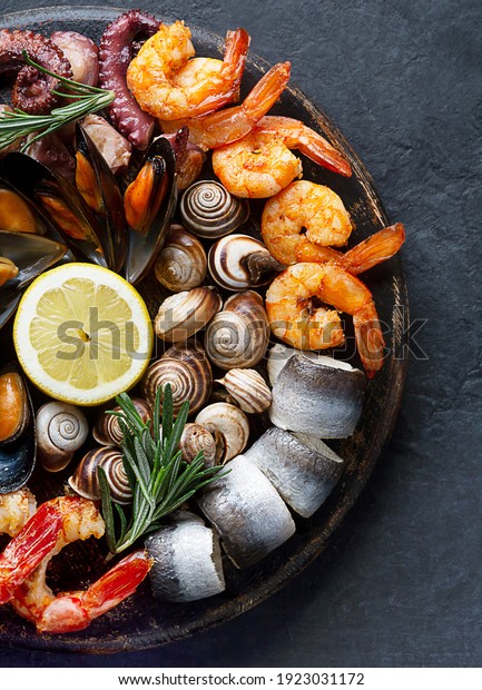 Seafood charcuterie\
platter board with shrimp, oysters, fish and octopus on black\
background. Top view, close\
up