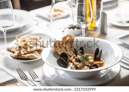 Seafood and fish soup served in an Italian restaurant in a fancy setting.