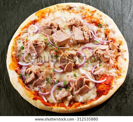 Seafood Italian pizza with tuna fillet, onions, fresh herbs and mozzarella on tomato served uncut on a crusty base viewed from above