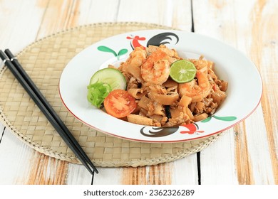 Seafood Kwetiau Goreng with Egg, Shrimps, Fish Meatball, and Lime. Stir Fry Char Kway Teow with Prawn On White Table 