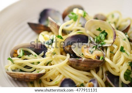 Seafood Pasta with mussels and basil in white plate on wooden table.