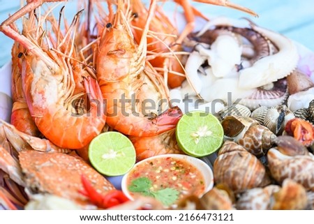 seafood plate with shrimp shellfish crab squid cockle spotted babylon with seafood sauce chili lemon lime serve on dining table, shrimps prawns seafood buffet menu cooked food