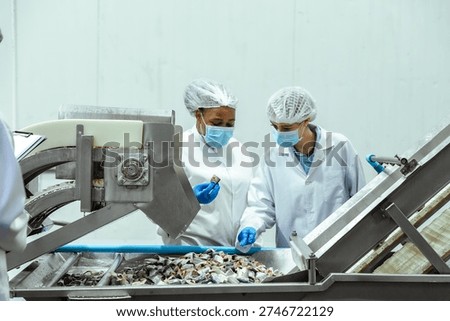 Seafood processing technicians evaluate product texture and appearance at preparation stage inside food manufacturing facility. Concept reflects safety standards, risk prevention and export certification readiness.