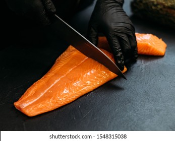 Seafood restaurant. Closeup of chef hands using knife to cut fresh salmon fillet. Copy space. - Powered by Shutterstock