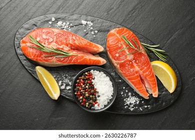 Mariscos. Filetes de salmón, especias y gajos de limón en mesa con textura negra, vista superior