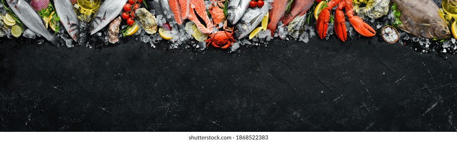 Seafood. Set of fish, crustaceans, oysters, mussels and seafood on a black stone background. Free space for your text.