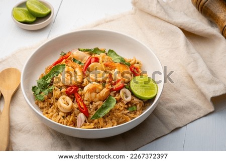 Seafood Tom Yum Fried Rice,Stir fried rice with shrimp and squid with chilli sauce on white plate