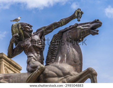 A seagull sits on top of the head of a native American Indian on horse statue.