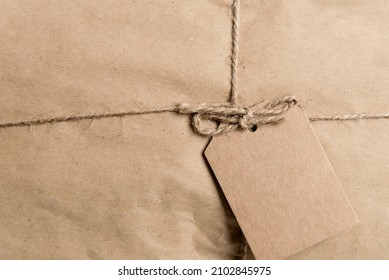 Sealed Package In Paper And Tied With Thread And Blank Sticker For A Message Or Address. Paper Parcel With Craft Blank Label.