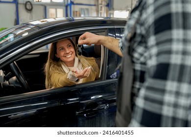 Sealing the deal with a smile: A white mechanic passes car keys to a happy customer, embodying quality service and customer satisfaction in the workshop.  - Powered by Shutterstock