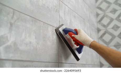 Seam grouting with black grout. Tile grout. Construction work with ceramic tiles. Grouting, joining wall tiles. The builder processes the seams between ceramic tiles.
