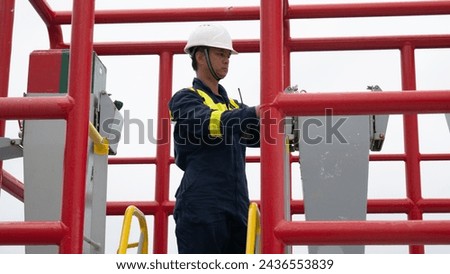 Seaman crew member of cargo vessel  equipped with personal protective equipment operate mooring winch from shelter position on cargo ship