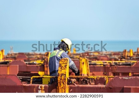 Seaman working on deck of the container vessel. He is preparing ship to enter shipyard.