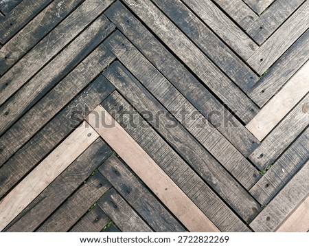 Seamless herringbone patterned outdoor deck or wood parquet. Flooring made from reclaimed or salvaged wood. weathered and discolored rough planks. nails or screws visible at each joint.