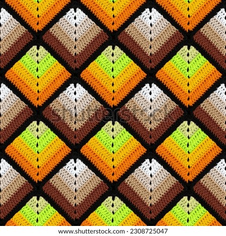 Seamless knitted pattern in the form of gradient rhombuses is crocheted with multi-colored threads. Patchwork style. Acrylic blanket.