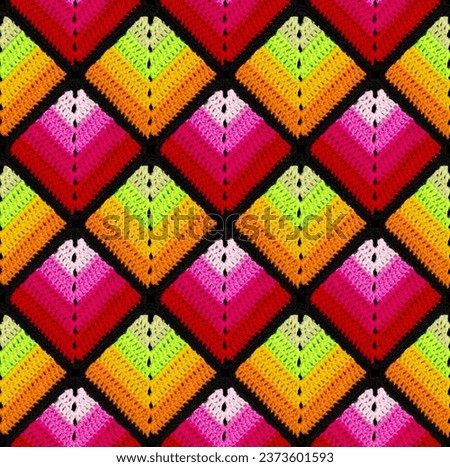 Seamless knitted pattern in the form of gradient rhombuses is crocheted with multi-colored threads. Patchwork style. Acrylic blanket.