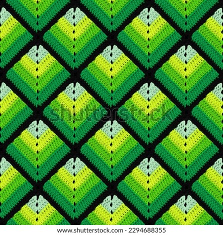 Seamless knitted pattern in the form of green gradient rhombuses is crocheted with multi-colored threads. Patchwork style. Acrylic blanket.