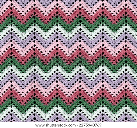 Seamless knitted pattern in the form of openwork zigzags crocheted with threads of contrasting colors. Acrylic baby yarn. African style.