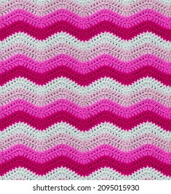 Seamless knitted pattern in the form of zigzags is crocheted with multi-colored threads. Acrylic baby yarn. Contrasting pink range of shades.