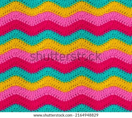 Seamless knitted pattern in the form of zigzags is crocheted with bright multi-colored threads. Acrylic baby yarn. African style.