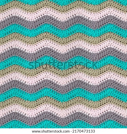 Seamless knitted pattern in the form of zigzags is crocheted with multi-colored threads. Acrylic baby yarn. Pastel shades.