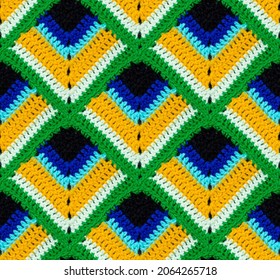 Seamless knitted texture. The pattern in the form of a peacock feather is crocheted with multi-colored threads. Acrylic baby yarn. Colorful background.
