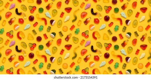 Seamless pattern of assorted jelly gum fruit candy on yellow background top view flat lay
