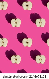 seamless pattern of halves of apples on a pink background with hard sunlight. High quality photo