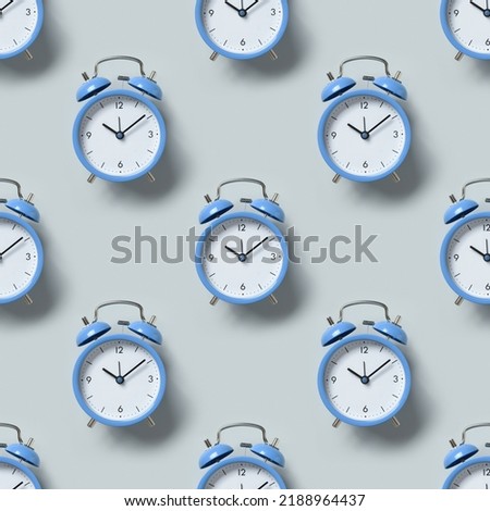Seamless pattern of old-fashioned blue alarm clocks on blue background. Flat lay.