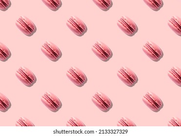 Seamless pattern of pink macaron pastry french cookies on background with hard light shadow.