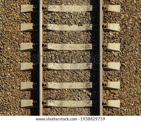 Seamless railroad Pattern, backdrop with space for text. Top view. Shiny iron rails and concrete sleepers, coupled with powerful bolts on stony ground, fortified rubble overgrown