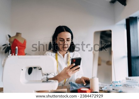 Seamstress browsing mobile phone phone at work
