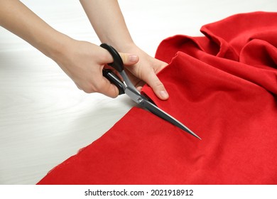 Seamstress cutting red fabric with scissors at workplace, closeup - Powered by Shutterstock