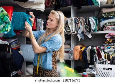 A seamstress removes a fabric beam from a rack. Tailor's workshop. - Shutterstock ID 2187136773