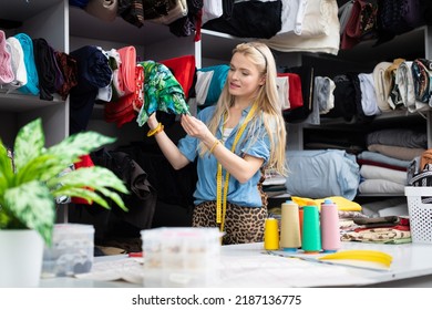 A seamstress removes a fabric beam from a rack. Tailor's workshop. - Shutterstock ID 2187136775