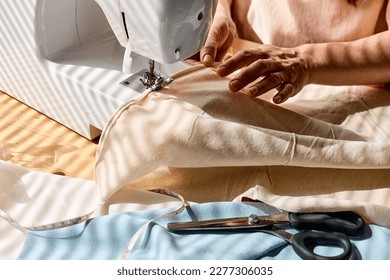 Seamstress sewing linen fabric on sewing machine in small studio. Fashion atelier, tailoring, handmade clothes concept. Slow Fashion. Conscious consumption. - Powered by Shutterstock