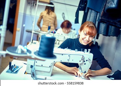 seamstress sews clothes. Workplace of tailor - sewing machine, rolls of thread, fabric, scissors.