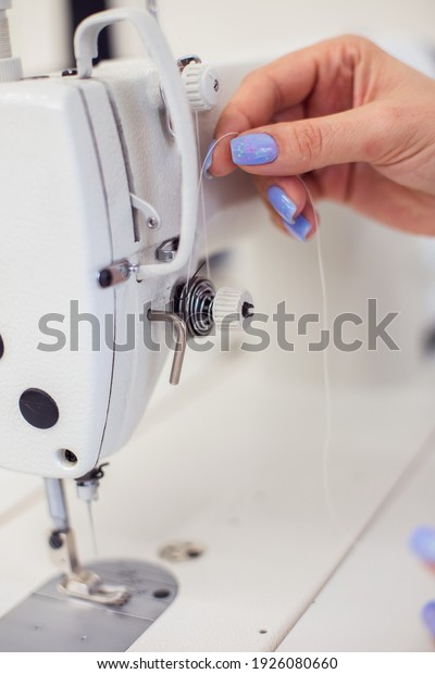 a seamstress sits and\
sews on a sewing machine. Insert the thread into the needle. A\
tailor sews clothes at his workplace. Hobby sewing as a small\
business concept