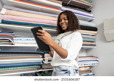 Seamstress using tablet to order fabrics online checking all materials in stock in her atelier - Powered by Shutterstock