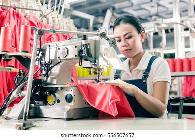 Seamstress or worker in Asian textile factory sewing with  industrial sewing machine