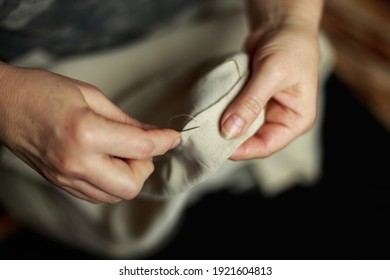 Seamstress's hands. Female hands with a needle, thread and thimble. Woman sews clothes. Conceptual idea.