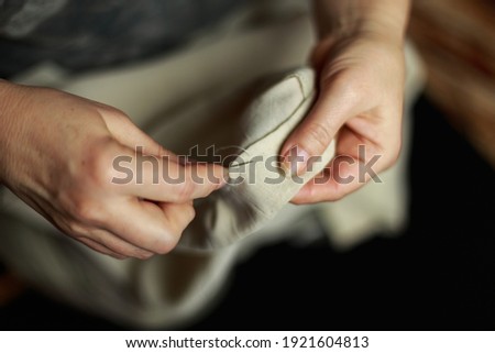 Seamstress's hands. Female hands with a needle, thread and thimble. Woman sews clothes. Conceptual idea.