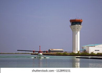 Seaplane Landing On The Water With The Air Traffic Control Tower In The Background