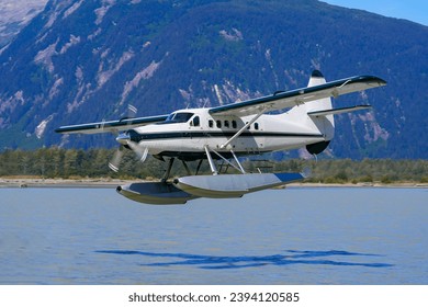 Seaplane taking off from a melt water lake in the Alaskan mountains north of Juneau in the Taku inlet