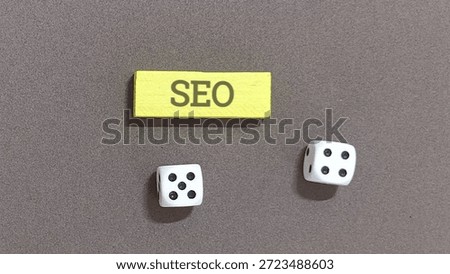 Search engine optimization concept shown by a yellow block with seo text positioned above two small white dice.