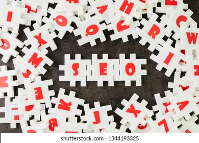 Search Engine Optimization, SEO concept, white puzzle jigsaw with alphabet building the word SEO at the center of dark chalkboard.