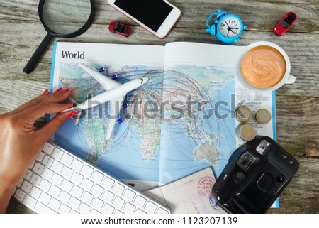 Search flight tickets online with woman looking for travel destination on map surrounded by travel objects
                               