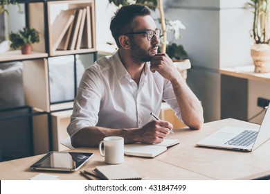 In search of inspiration. Thoughtful mature man holding pen and looking away while sitting at his working place in office  - Powered by Shutterstock