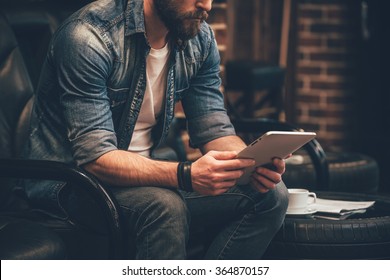 In search of new ideas. Close-up of young bearded man holding digital tablet and sitting in chair  - Shutterstock ID 364870157