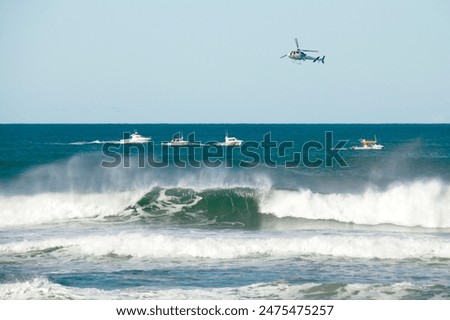 Search and rescue helicopter and boat operation at sea looking for missing fisherman washed from rocks on Australia's east coast in the Pacific Ocean